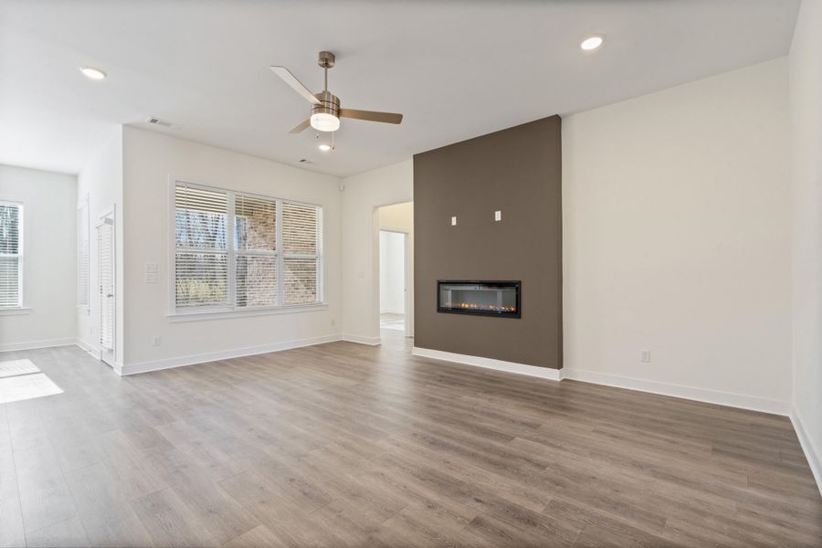Unfurnished living room featuring a ceiling fan, recessed lighting, a glass covered fireplace, and light wood-style floors