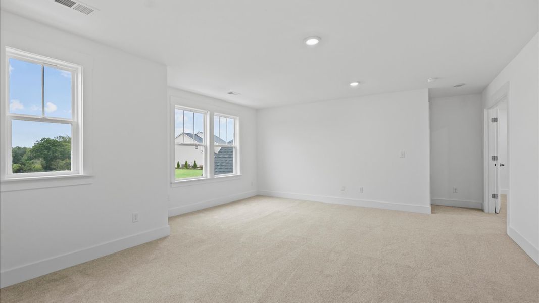 Vibrant carpeted loft offering flexibility as a study nook, game room, or second family space