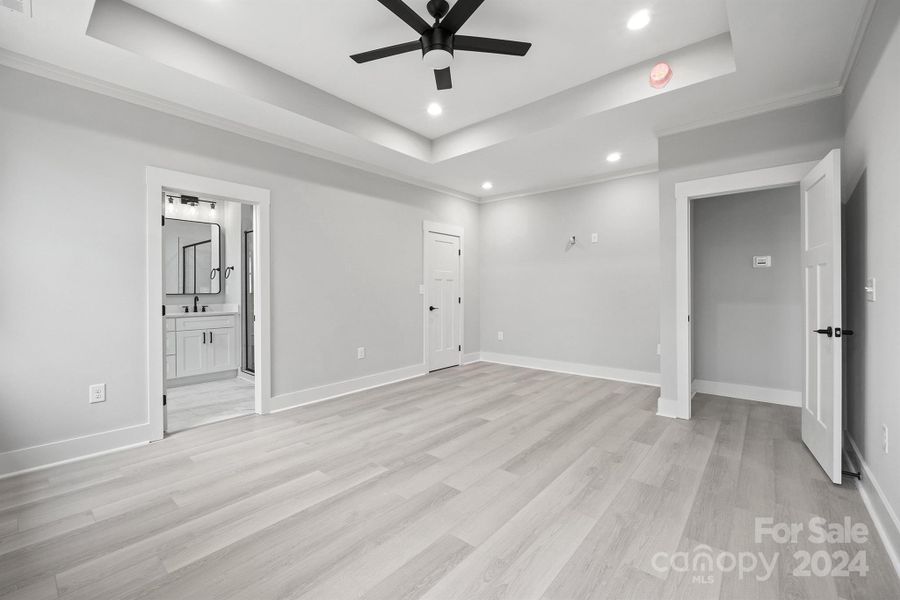 Primary bedroom with large ceiling fan and tray ceilings