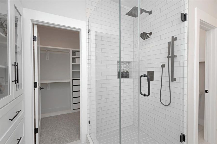 A Frameless Glass Shower with a Luxury Dual Shower Head System and a Built-In Custom Cabinet with Glass Doors and Deep Drawers elevate the spa-like experience. A Frameless Glass Shower with a Luxury Dual Shower Head System and a Built-In Custom Cabinet with Glass Doors and Deep Drawers elevate the spa-like experience.