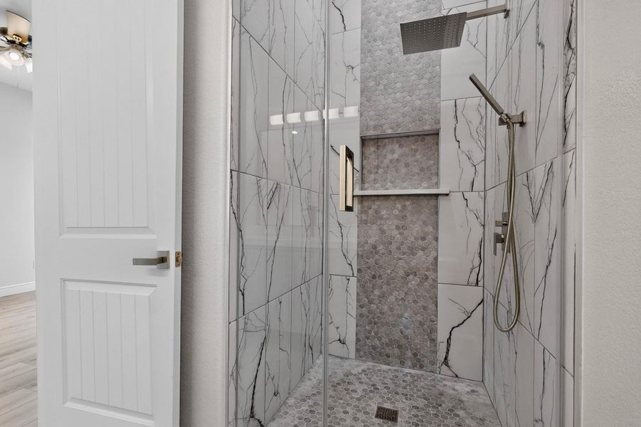 Custom tiled walk-in shower features a rain showerhead and glass enclosure.