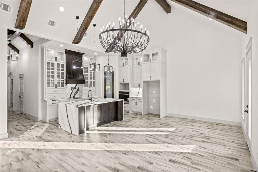 Kitchen with glass insert cabinets, arched walkways, high vaulted ceiling, beam ceiling, and white cabinets Kitchen with glass insert cabinets, arched walkways, high vaulted ceiling, beam ceiling, and white cabinets