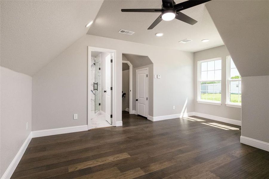 Bonus room featuring visible vents, lofted ceiling, ceiling fan, and dark wood-type flooring Bonus room featuring visible vents, lofted ceiling, ceiling fan, and dark wood-type flooring