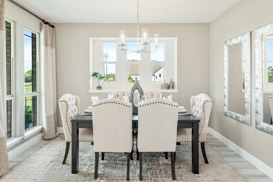 Dining room with dark wood table, six upholstered chairs, chandelier, and large windows with natural light