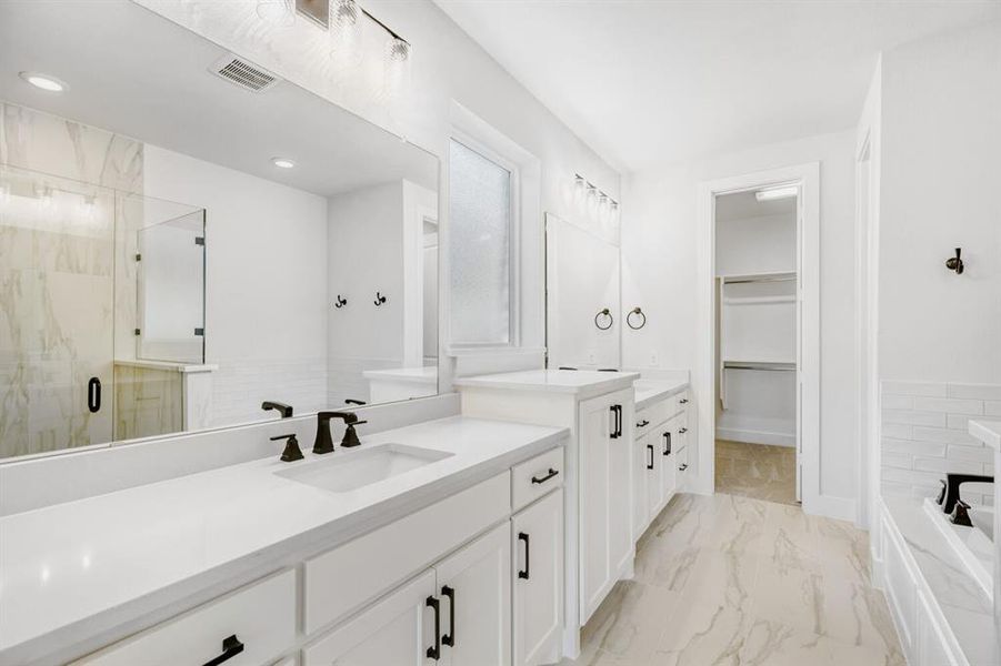Bright bathroom featuring dual vanities with white cabinetry and countertops