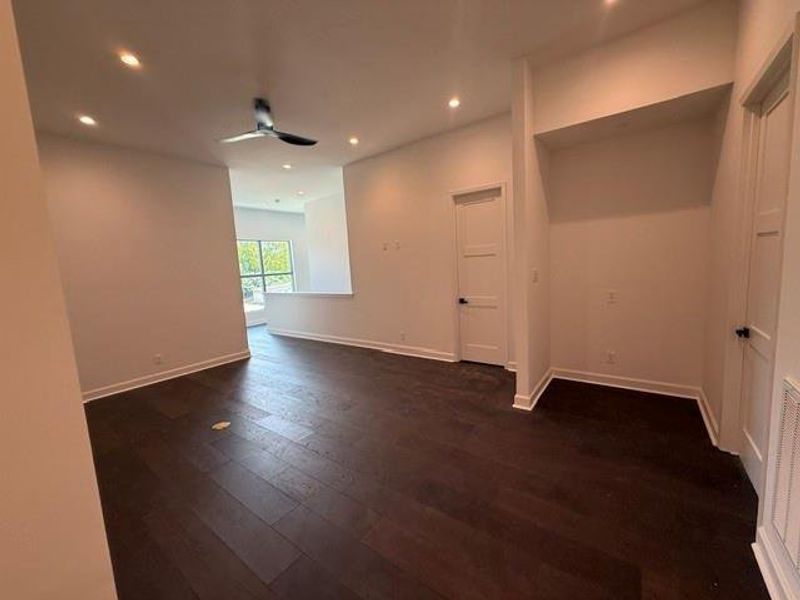 Spacious upstairs family room featuring rich hardwood floors, recessed lighting, and a ceiling fan, with a bright window nook for natural light.