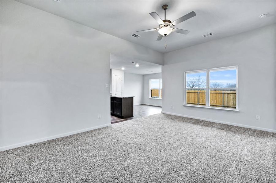 Unfurnished living room featuring carpet and ceiling fan