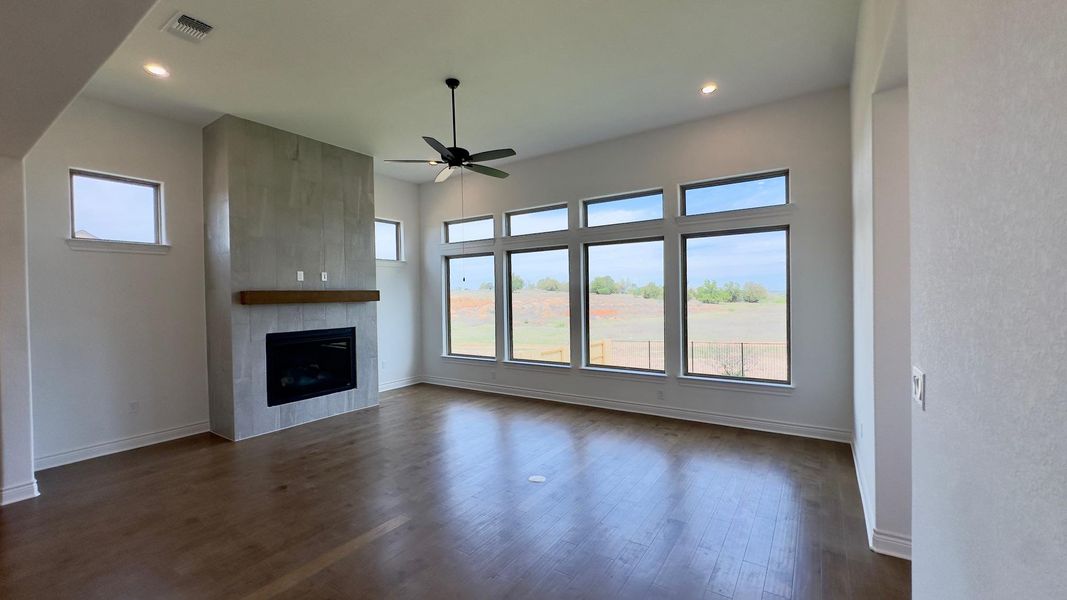 Unfurnished living room featuring ceiling fan, dark wood finished floors, a fireplace, and recessed lighting