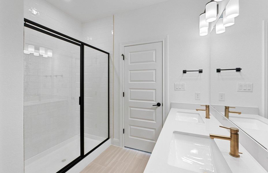 Full bathroom featuring double vanity, a shower stall, and a chandelier Full bathroom featuring double vanity, a shower stall, and a chandelier