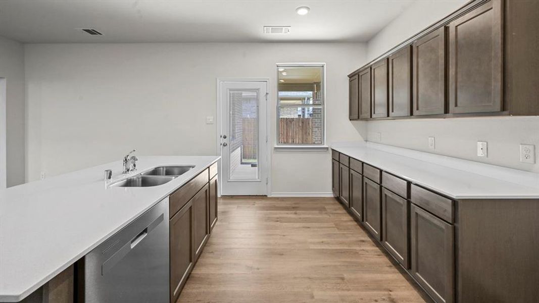 Contemporary kitchen featuring an expansive island with a double basin sink and integrated dishwasher