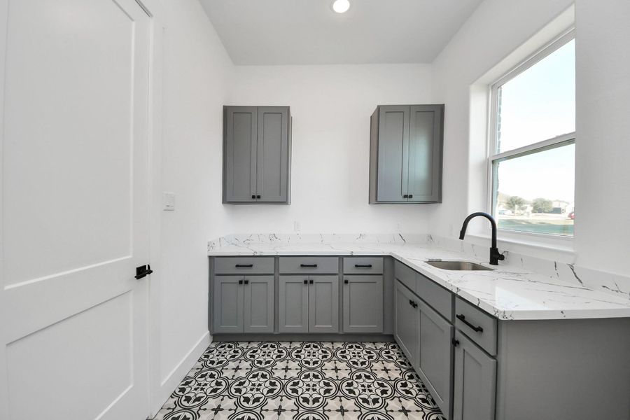 Luxury laundry room with custom cabinetry, counter and sink.