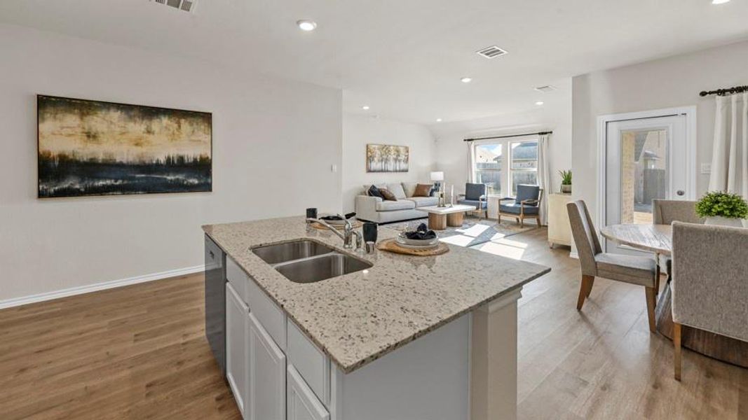 Kitchen featuring light wood-style floors, an island with sink, open floor plan, light stone countertops, and white cabinets