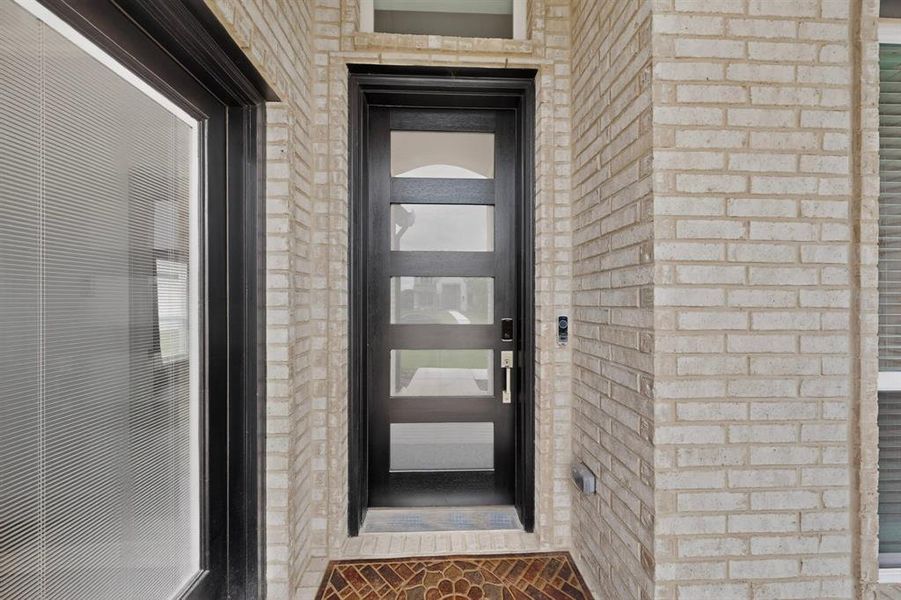 Modern black entry door with frosted glass panels, complemented by light-colored brick exterior Modern black entry door with frosted glass panels, complemented by light-colored brick exterior
