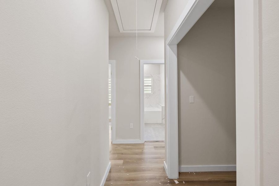 Hallway featuring attic access and light wood-type flooring Hallway featuring attic access and light wood-type flooring