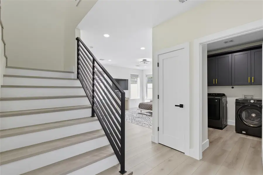 Laundry room featuring cabinet space, recessed lighting, light wood-style floors, and washing machine and clothes dryer
