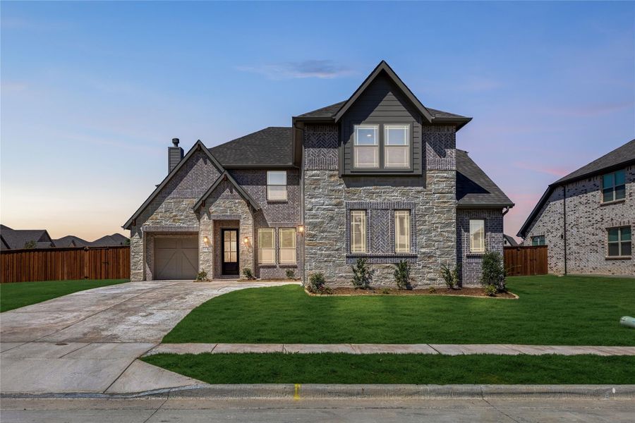 Two-story home with stone and brick exterior, single-car garage, and manicured front lawn at dusk Two-story home with stone and brick exterior, single-car garage, and manicured front lawn at dusk