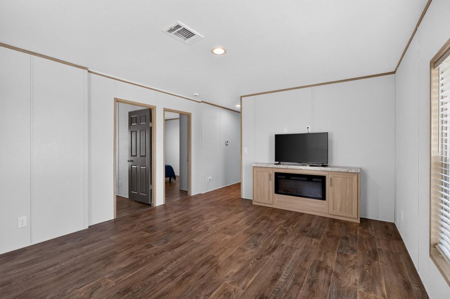 Laminate flooring extends throughout this naturally illuminated living space, featuring an entertainment center with an electric fireplace.