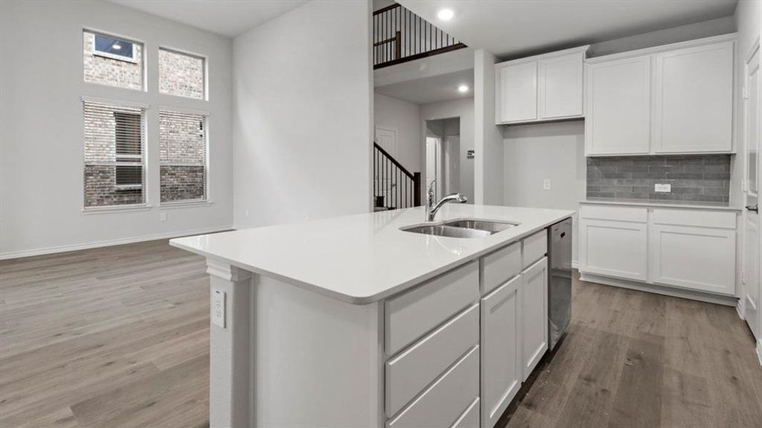 Kitchen with white cabinetry, a kitchen island with sink, light wood finished floors, recessed lighting, and light stone countertops
