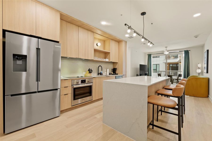 Warm wood cabinetry and a stone-waterfall island anchor this modern open-concept kitchen.