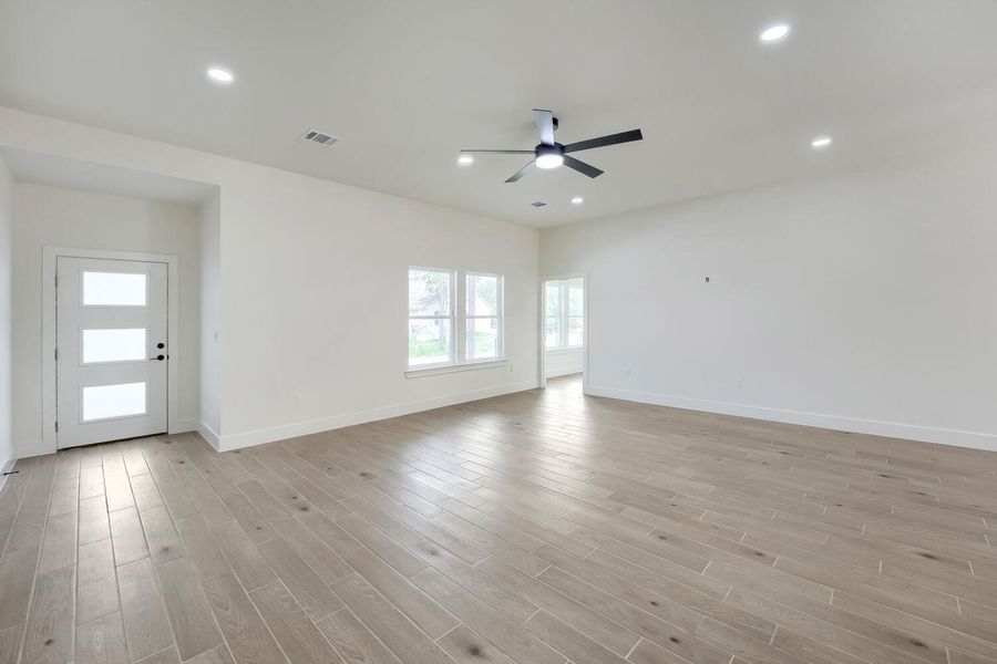 A naturally illuminated living area showcases sleek wood-look tile flooring and contemporary recessed lighting.