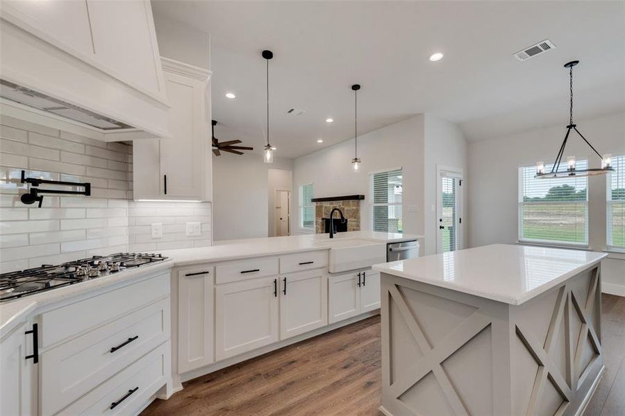 Kitchen with light hardwood / wood-style flooring, sink, hanging light fixtures, backsplash, and ceiling fan with notable chandelier