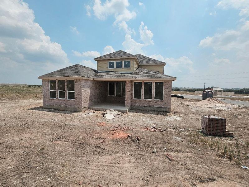 Rear view of property featuring a patio area, brick siding, and roof with shingles Rear view of property featuring a patio area, brick siding, and roof with shingles