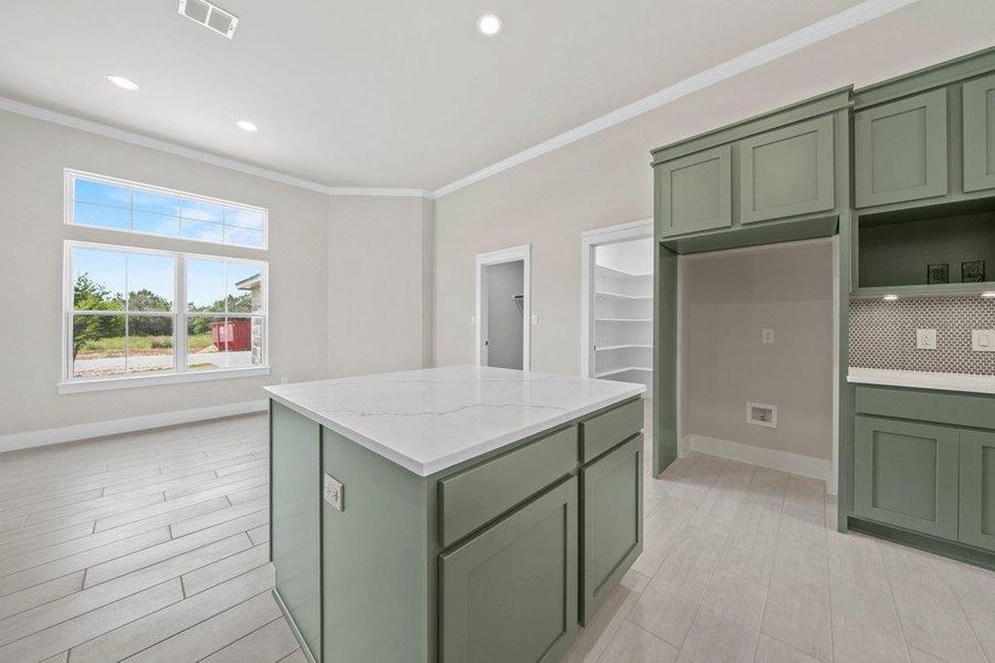 Kitchen featuring green cabinetry, ornamental molding, baseboards, and recessed lighting Kitchen featuring green cabinetry, ornamental molding, baseboards, and recessed lighting