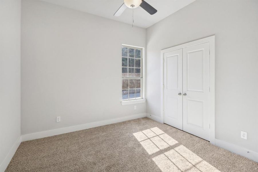 Unfurnished bedroom with ceiling fan, light colored carpet, and a closet