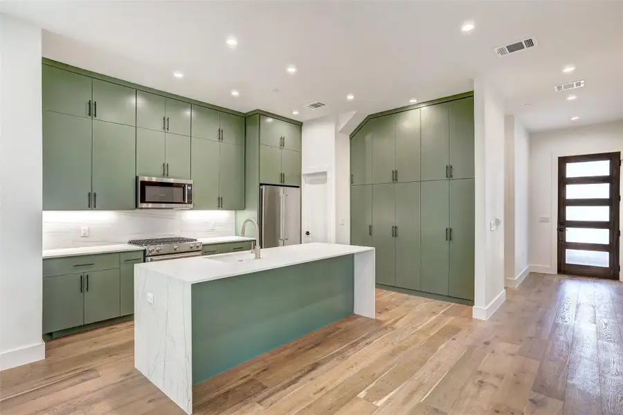 Kitchen featuring green cabinets, premium appliances, backsplash, light countertops, and recessed lighting
