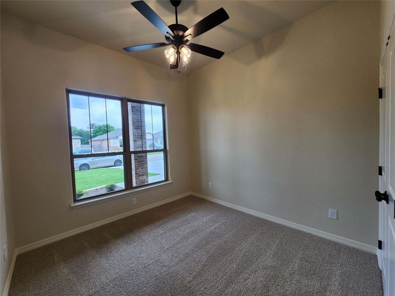Carpeted room featuring a ceiling fan with integrated lighting, a large window with multiple panes, and light-colored walls