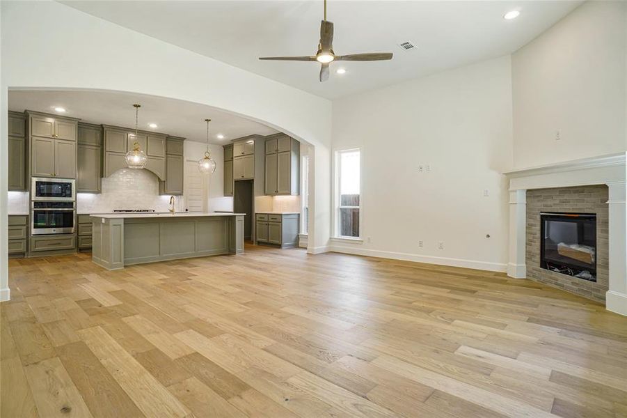 Kitchen with open floor plan, a center island with sink, gray cabinetry, a breakfast bar, and light countertops