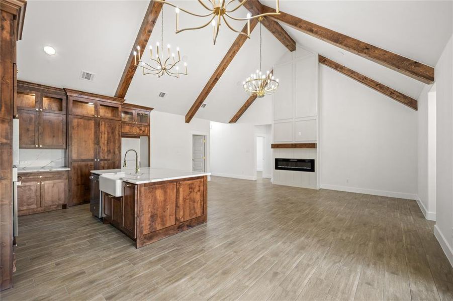 Kitchen featuring stainless steel dishwasher, dark wood-style floors, light stone counters, vaulted ceiling with beams, and decorative backsplash