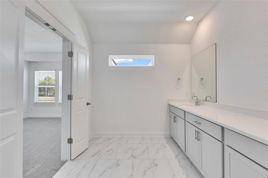 Bathroom featuring vanity, light marble finish flooring, vaulted ceiling, and recessed lighting