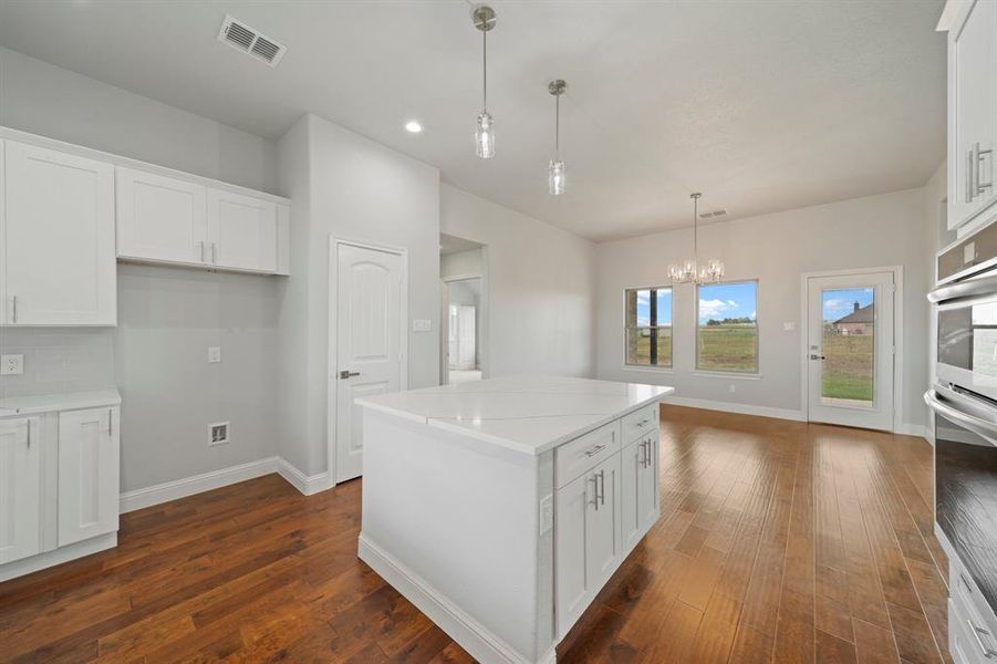 Kitchen with a center island, white cabinets, and dark wood-type flooring