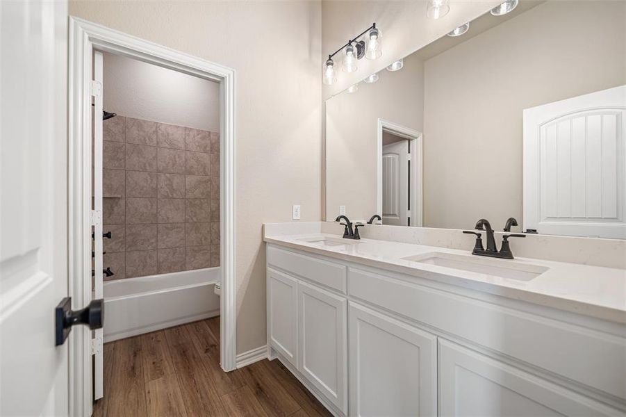 Full bathroom featuring dark wood-style flooring, double vanity, and shower / bath combination