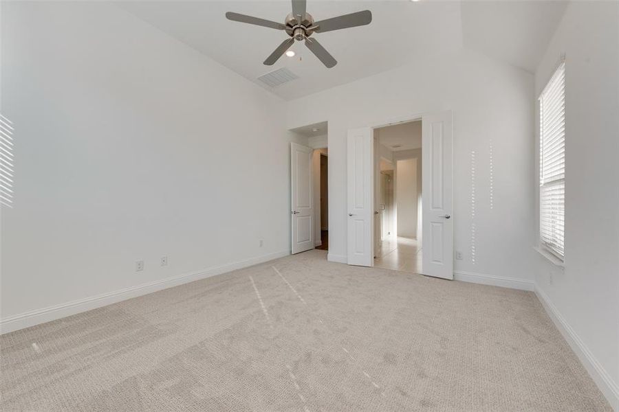 Unfurnished bedroom with ceiling fan, lofted ceiling, light carpet, and multiple windows