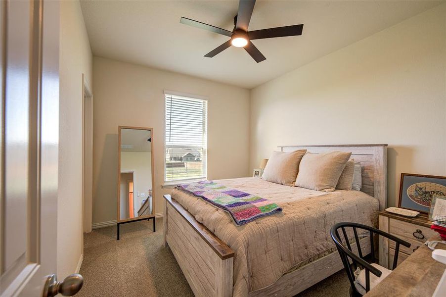 Carpeted bedroom featuring ceiling fan and baseboards