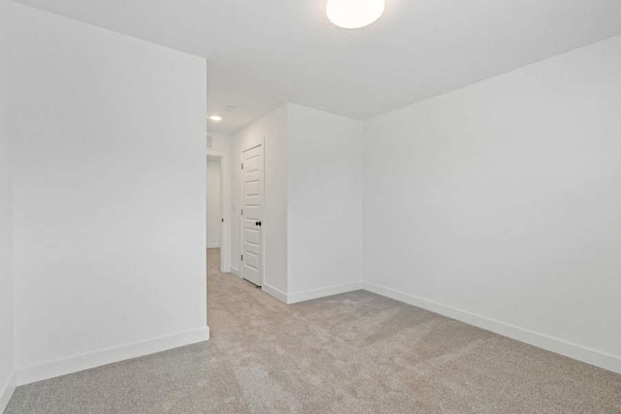 Carpeted room with a flush-mount ceiling light fixture, white walls, and white baseboards