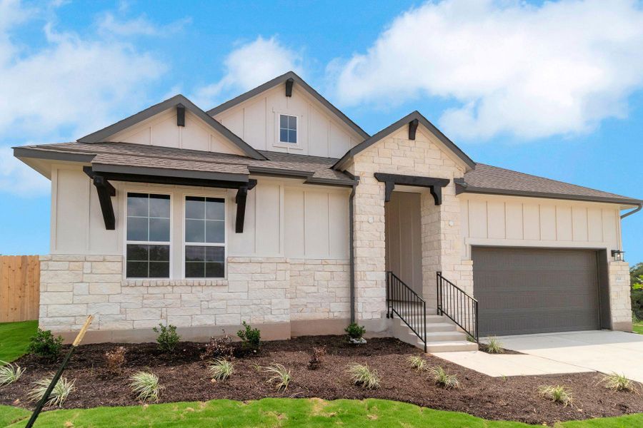 View of front of home featuring board and batten siding, stone siding, and a garage