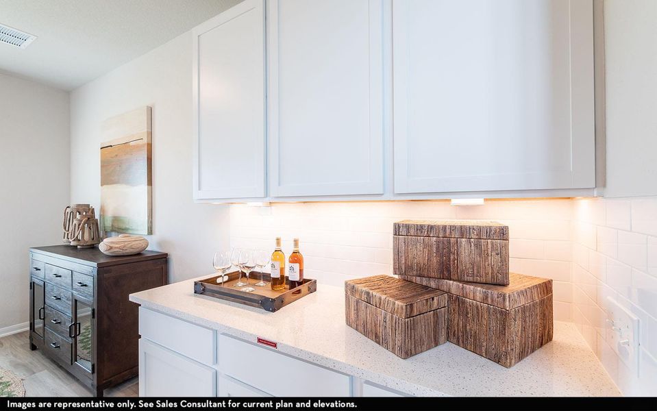 Bar area featuring light stone counters, white cabinets, and decorative backsplash