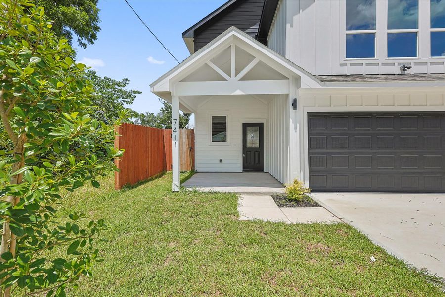 Close-up view of the covered front porch highlighting the inviting entryway and stylish front door with a glass panel. The clean white exterior, accented by black trim, creates a modern Craftsman look, while the porch offers a welcoming space to greet guests or relax outdoors. Photo of a different house with the same finishes. Close-up view of the covered front porch highlighting the inviting entryway and stylish front door with a glass panel. The clean white exterior, accented by black trim, creates a modern Craftsman look, while the porch offers a welcoming space to greet guests or relax outdoors. Photo of a different house with the same finishes.