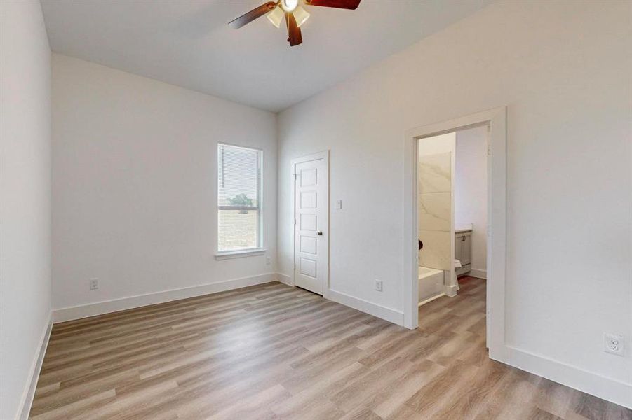 Unfurnished bedroom with a closet, ceiling fan, light hardwood / wood-style floors, and ensuite bath