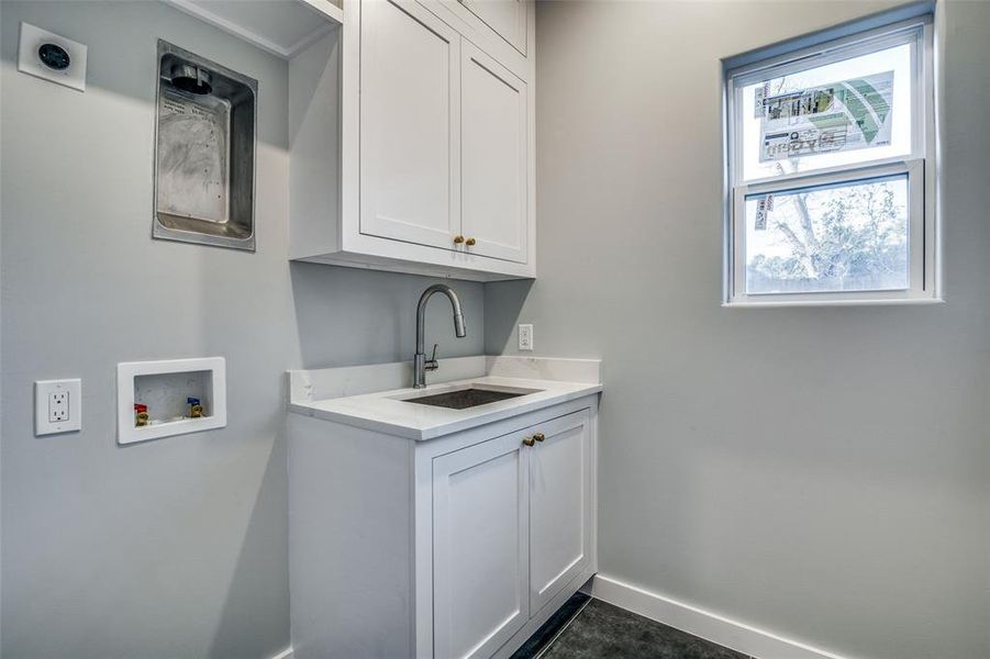 Clothes washing area featuring hookup for an electric dryer, washer hookup, cabinets, and sink