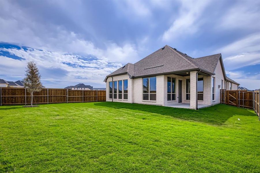 Rear view of property featuring brick siding, a fenced backyard, roof with shingles, and a patio area Rear view of property featuring brick siding, a fenced backyard, roof with shingles, and a patio area