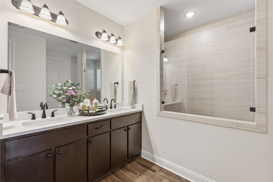 Bathroom featuring double vanity, a stall shower, and wood tiled floors