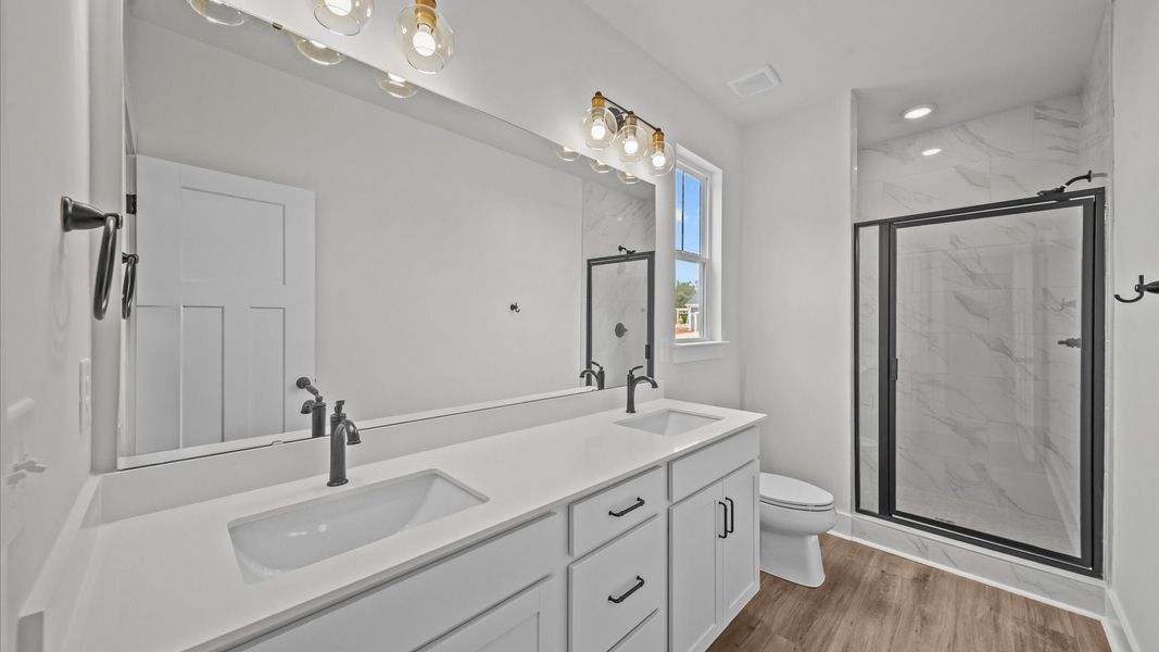 Superior en-suite primary bathroom with stylish dual vanity and tiled walk-in shower—crafted with high standards in mind