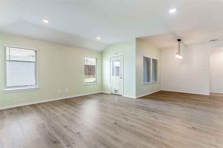 Spacious interior featuring wood-finish flooring, vaulted ceilings, and recessed lighting Spacious interior featuring wood-finish flooring, vaulted ceilings, and recessed lighting