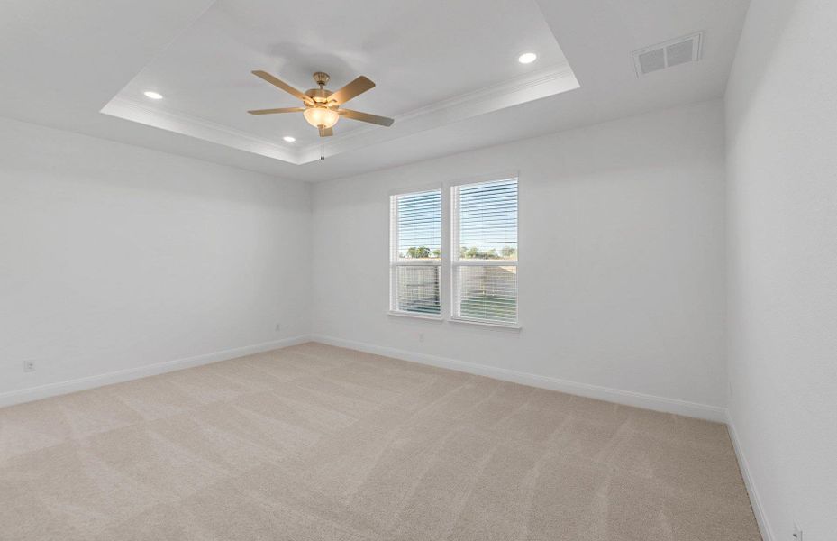 Empty room with light carpet, a raised ceiling, crown molding, recessed lighting, and ceiling fan