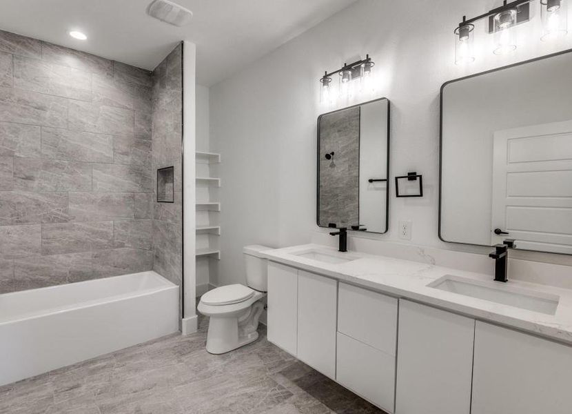 Full bathroom featuring toilet, tiled shower / bath, tile patterned flooring, and dual bowl vanity