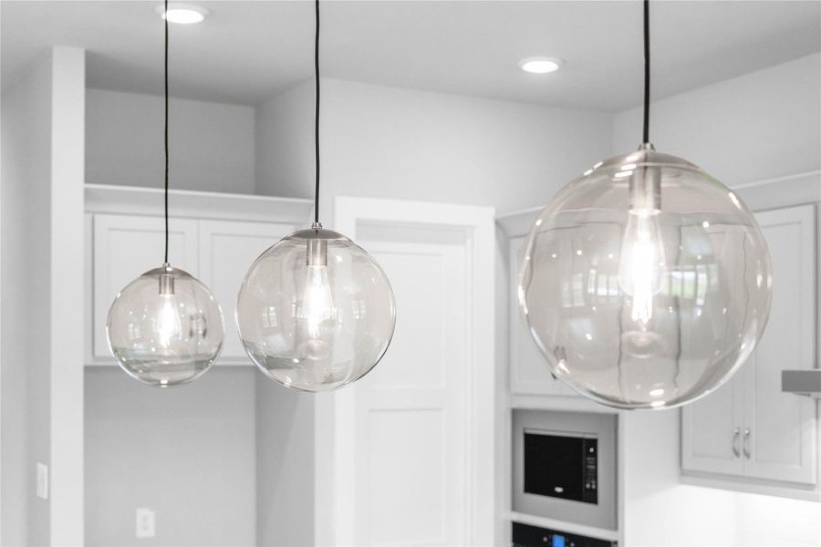 Contemporary pendant lights hang above the island, adding a touch of modern design, complemented by recessed lighting throughout the ceiling for overall illumination.